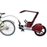 Bike with a red child trailer attached behind for transporting a kid.