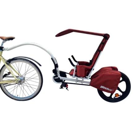 Bike with a red child trailer attached behind for transporting a kid.