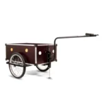 Red wooden two-wheeled wagon with a long black handle, used for hauling cargo or supplies.
