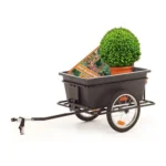 Black two-wheeled garden cart with a handle, carrying a potted topiary and a magazine.