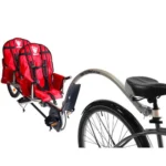 Red two-seat bicycle trailer attached to a bicycle, designed for transporting kids on a ride.