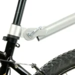 Close-up of a folding bicycle frame latch and hinge near the front wheel.