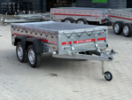 Two-axle aluminum cargo trailer with a grey tarp and red Temared branding, parked on a paved lot.