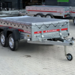Dual-axle silver utility trailer with a tarped bed, strapped sides, and a front jockey wheel, branded Temared.