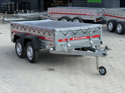 Dual-axle silver utility trailer with a tarped bed, strapped sides, and a front jockey wheel, branded Temared.