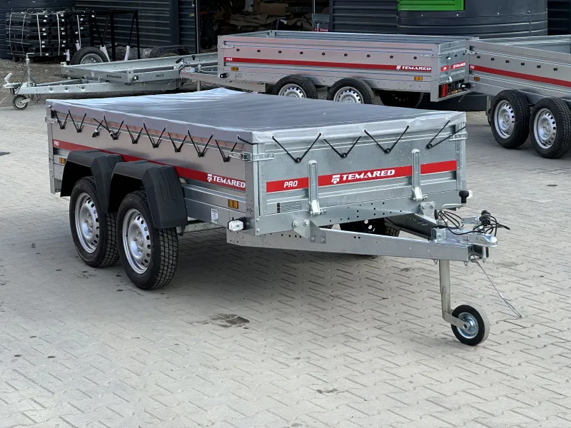 Remorque-a-deux-essieux-264×126-cm-voiture-avec-bache-plate-PRO-26122- 1 - NEVORIXT Dual-axle silver utility trailer with a tarped bed, strapped sides, and a front jockey wheel, branded Temared.