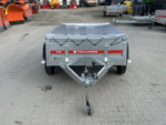 Front view of a grey utility trailer with a tarped bed and red Temared Pro branding, on a paved lot.