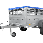 Metal livestock trailer with ventilation openings and a front hitch, designed to transport cattle or animals.