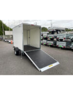 Enclosed white cargo trailer with a lowered ramp, parked on a lot with other trailers; empty interior ready for loading.