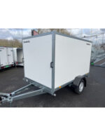 White Brenderup enclosed cargo trailer with front hitch and single axle, parked on asphalt.