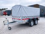 Tow trailer with a large gray tarp covering a cargo area, mounted on two axles with gray metal frame and red Temared branding, parked on a paved lot.